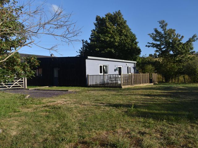 A cabin with a deck and surrounding grass at Pet friendly Cabin Sleeps 6 with Parking and Garden Penygroes