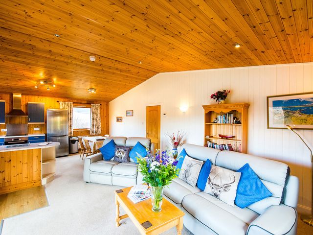 A living room with a sofa and dining area at Raven Lodge with beautiful views of Loch Dochart near Crianlarich