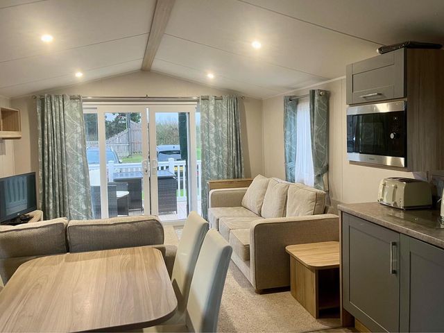 A living room with a sofa and dining table at Surfside Bliss Cayton Bay Park caravan Cayton Bay