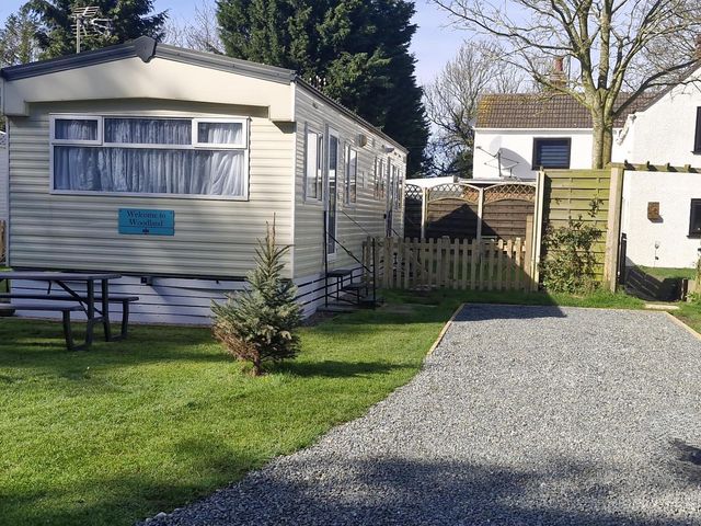 An outdoor view of a static caravan in the garden at Woodland View Dog Friendly Nr Sutton on Sea Thurlby near Alford