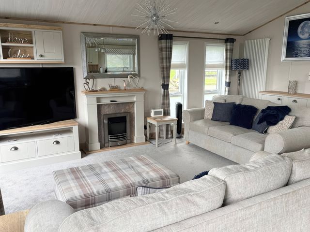 A living room with a television and fireplace at Harrogate Lodge Sleeps4 South Facing Decking Lufflands Caravan Park near Holsworthy