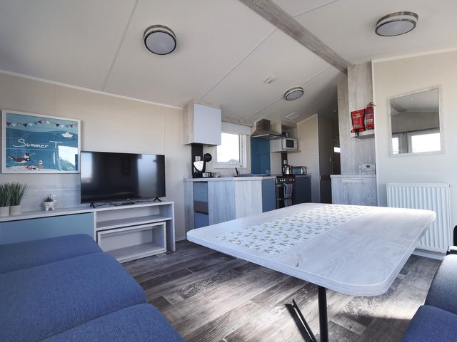 A living room with a television and kitchen area at the property
