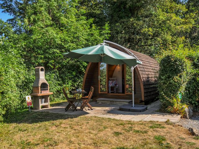 A garden with a wooden cottage and outdoor seating at Yar Tor in Tavistock