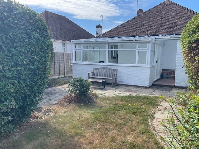 A garden with a bench and bushes at Summer Cottage in Rustington