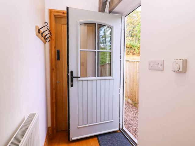 An entrance hall with a door and coat hooks at The Burrow at Aveling Cottage in Lydney