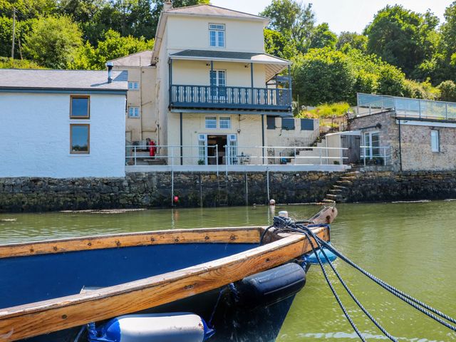 A house with a balcony and boat in the water at Shipwrights in Brixham