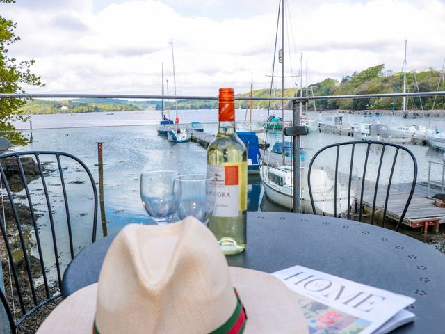 An outdoor area with a wine bottle and glasses overlooking water and boats at Spanish Boathouse in Brixham