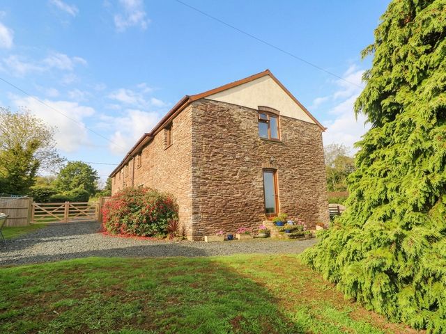An outdoor view of a stone building with a garden at Greig House Farm in Abergavenny