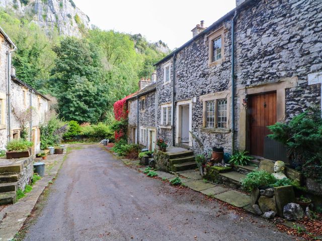 A pathway with stone houses and plants at 73 Ravensdale Cottages in Cressbrook near Litton, Derbyshire