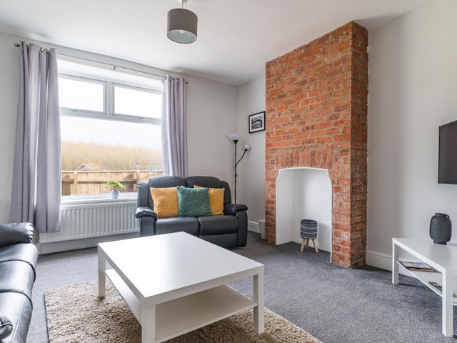 A living room with a brick fireplace and sofa at East House-Sleeps 5-Pet friendly-Garden-Parking in Stakeford
