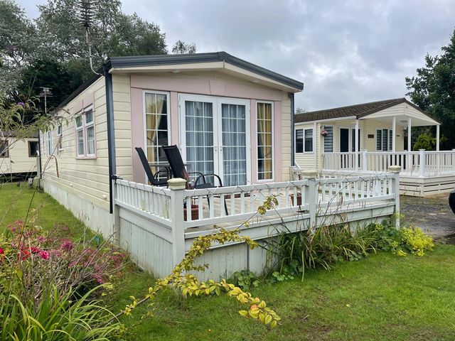 A lodge with a deck and chairs at 2 Bed Lodge Sleeps 5 - Pet Friendly, WiFi, Parking, Skegness