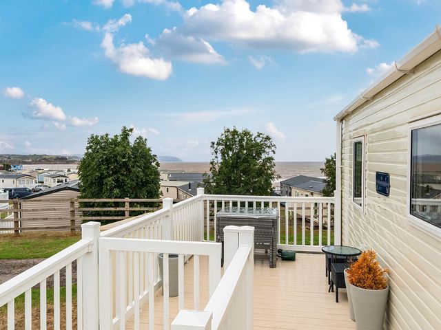 An outdoor area with a deck and chairs at Cabin - Sleeps 4 - Pets Ok - Balcony - Parking in Haven Park, Doniford Bay near Watchet