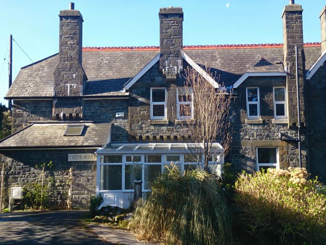 A stone house with a conservatory and multiple windows at Penbryn Mynach in Barmouth