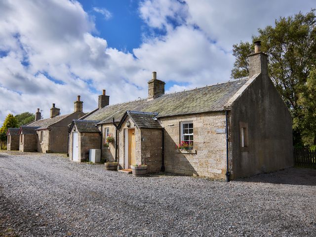 A view of multiple cottages with a gravel driveway near Edinburgh