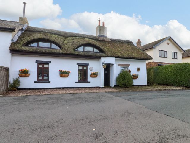 A house with a thatched roof and planters at The Thatched Cottage in Preston