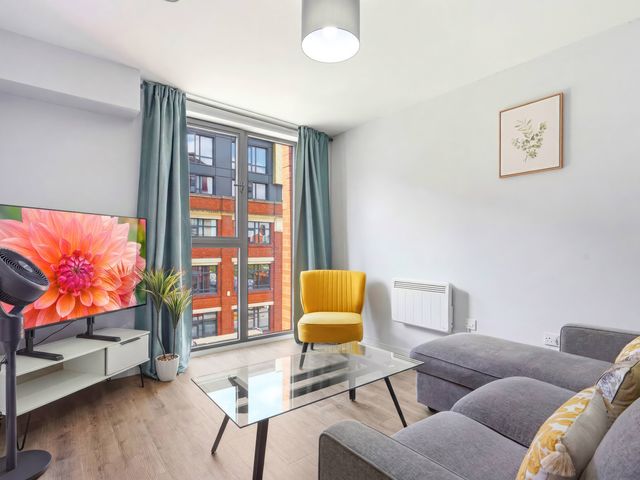 A living room with a yellow chair and television at Apartment 56 in Birmingham