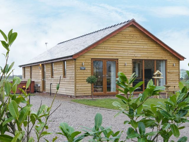 A wooden house with several windows and a garden at Woodman's Lodge Nantwich