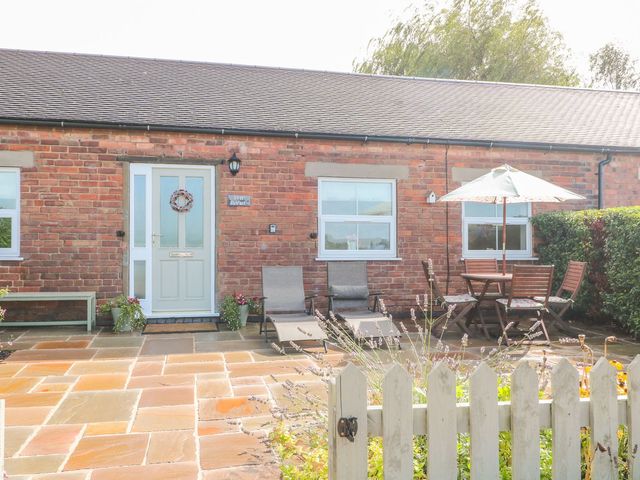 An outdoor area with a table and chairs in front of a door at The Byre in Ashbourne