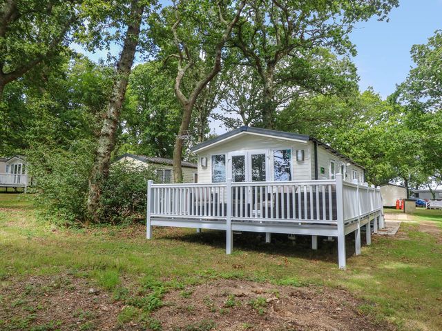 A cabin with a deck surrounded by trees at Serenity Thorness Bay in Cowes