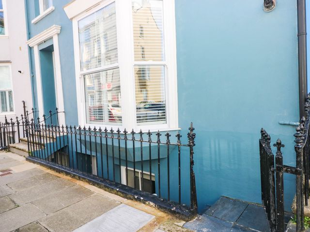 An outdoor view of a building facade with a window and railings at the Basement Apartment in Tenby