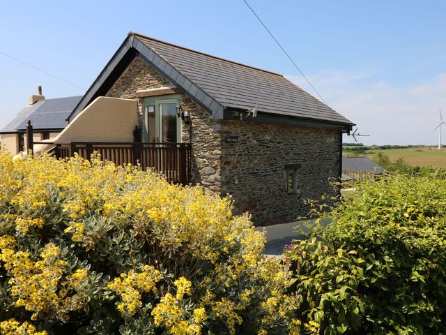 A stone house with a deck and flowering plants at Oak Cottage in Truro