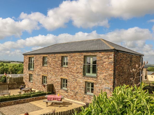 An outdoor view of a stone building with windows and patio at Hawthorn Cottage in Truro