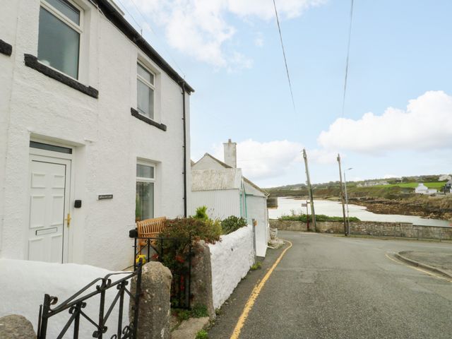 A house on the corner of a street with a bench outside at Mor Awelon Moelfre