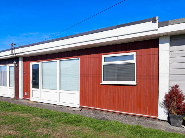 An exterior view of a red wooden wall with windows and doors at 122 Norton Park in Dartmouth