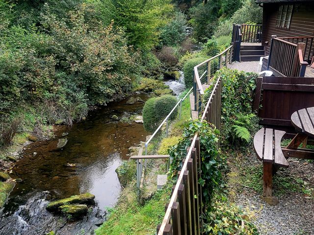 An outdoor area with a stream and seating at River Lodge in Lynbridge near Lynmouth