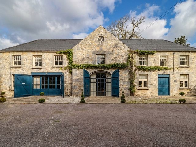 A stone building with blue doors and windows at The Bakery Hotel Room in Gileston near St Athan