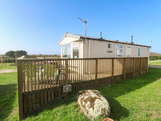 A cabin with a wooden deck and outdoor furniture at No.73 Sennen Cove