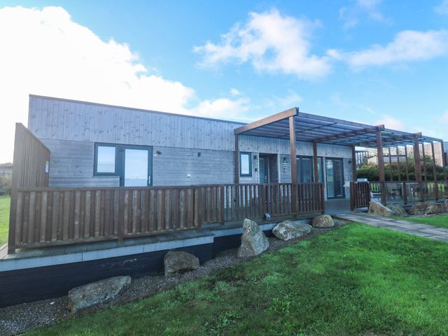 A wooden building with a deck and glass doors at 74 Porthmeor in Redruth