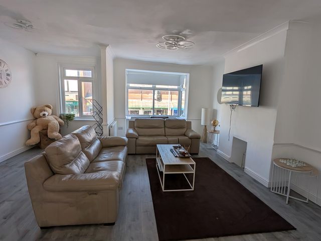 A living room with a television and a sofa at Spacious Duplex Flat in Thornton-Cleveleys