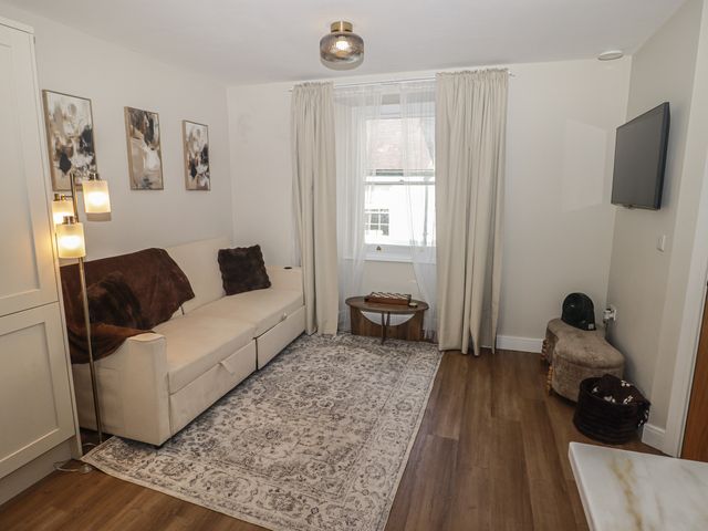 A living room with a sofa, lamp, and television at Flat 3 in Tenby