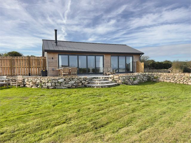 A building with a stone wall and chairs under the sky at Granfer’s near Penryn