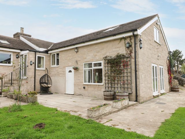 An outdoor area with a stone house and garden features at Greystones Apartment A near Buxton