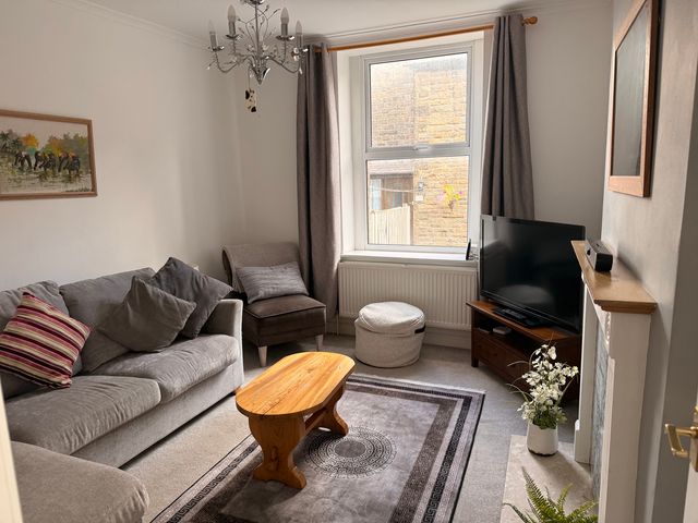 A living room with a sofa and tv at 9 Market View Buxton
