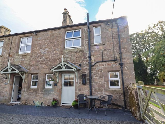 An outdoor view of a stone cottage with a table and chairs at The Gables in Alnwick