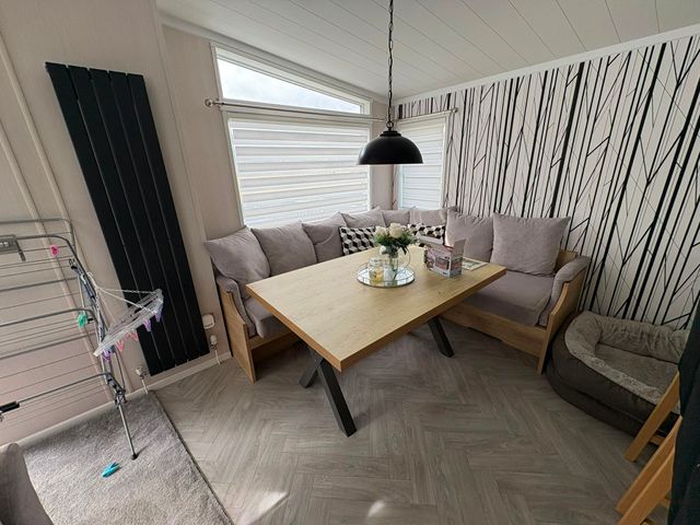 A dining room with a table and sofa at Ty Mawr Holiday Park Swift Toronto Lodge, Abergele