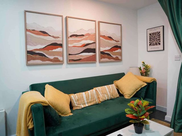 A living room with a green sofa and wall art at Ground Floor Apartment Sleeps 4 with Parking Cardiff