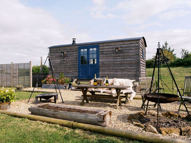 An outdoor area with a table and chairs near a wooden shed at Lillie's Shepherds Hut at Shepherds Lodge Retreat and Wellness Nottingham