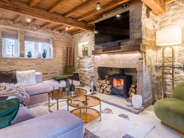 A living room with a fireplace and television at Heaven Lea Cottage
