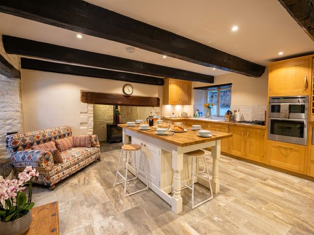 A kitchen with wooden cabinets and a central island at Tynewydd Farmhouse