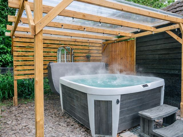 A hot tub under a wooden structure in a garden