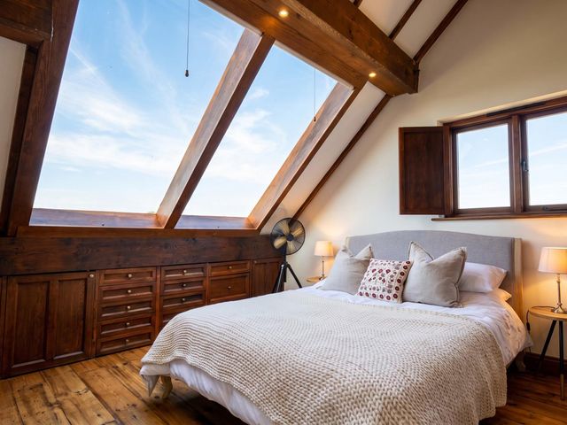 A bedroom with a bed, shelves, and windows at The Old Barn in Manchester