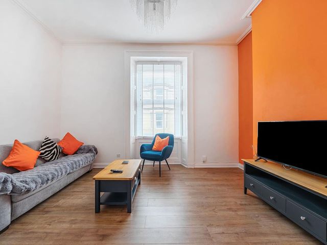 A living room with a sofa, armchair, coffee table, and television at the property in 