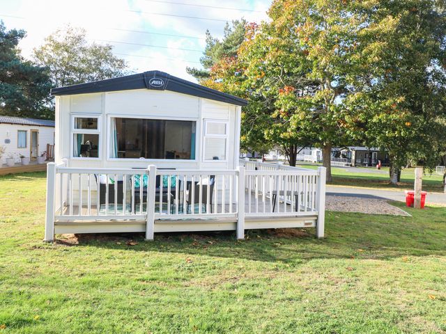 A mobile home with a deck in a grassy area at Four Seasons Great Yarmouth