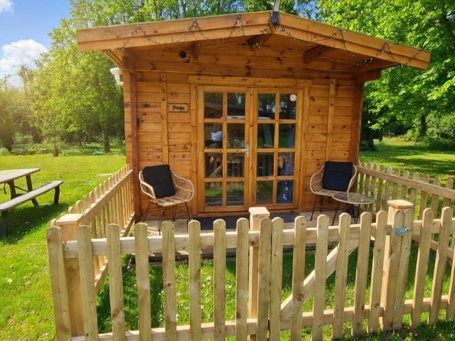 A wooden cabin with chairs and a table outdoors at Snowdrop Lodge Dog friendly Nr Anderby Creek in Alford