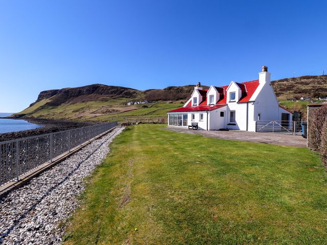 A house by the sea with a cliff in the background at Jubilee Cottage Uig