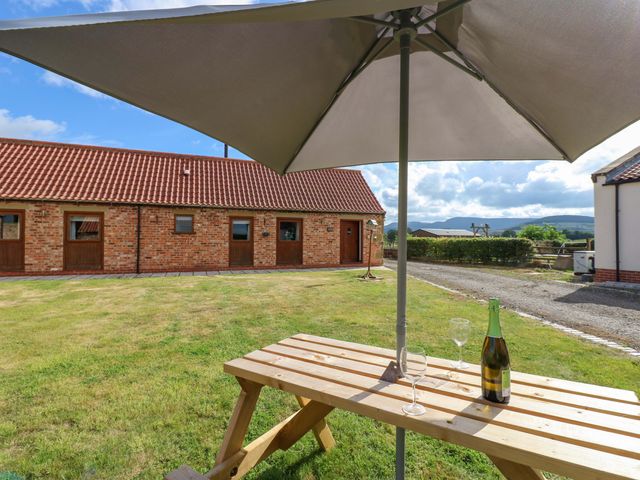 An outdoor seating area with a table and glasses at Pottowe Cottage in Potto near Stokesley